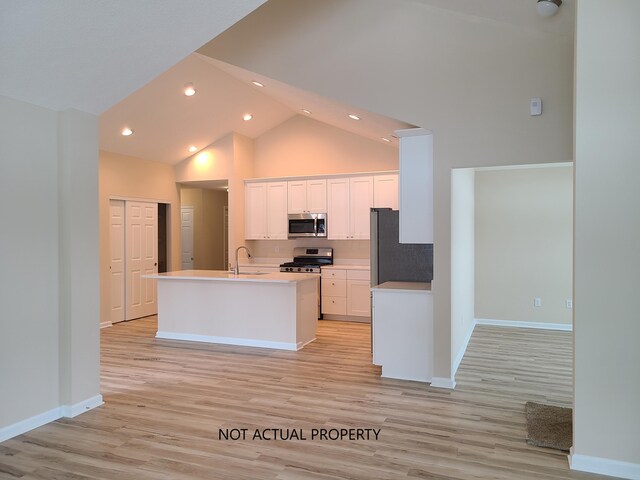 kitchen featuring high vaulted ceiling, white cabinets, sink, light hardwood / wood-style floors, and stainless steel appliances