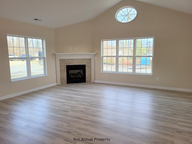 unfurnished living room with high vaulted ceiling and light hardwood / wood-style floors