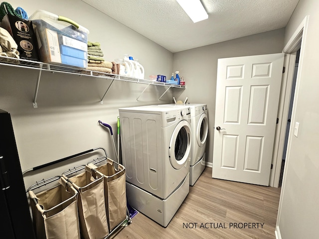 washroom with washer and clothes dryer, light hardwood / wood-style floors, and a textured ceiling