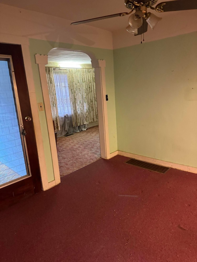 spare room with a wealth of natural light, ceiling fan, and dark carpet