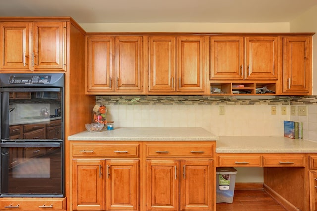 kitchen featuring hardwood / wood-style floors, backsplash, and double oven