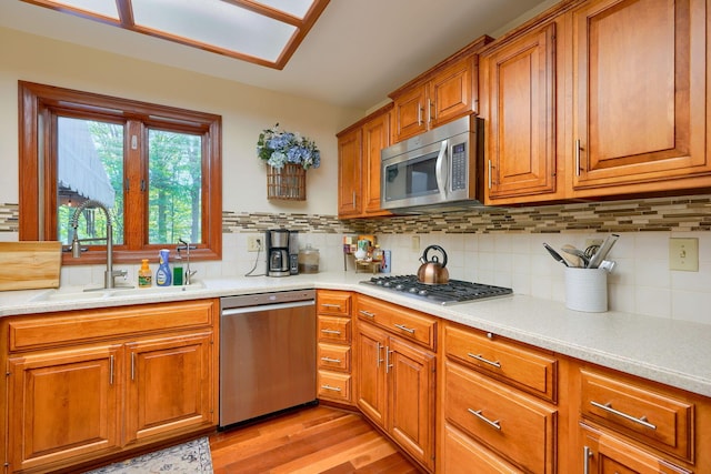 kitchen featuring light hardwood / wood-style floors, sink, stainless steel appliances, and tasteful backsplash