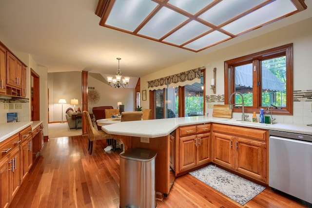 kitchen featuring backsplash, dishwasher, pendant lighting, and an inviting chandelier