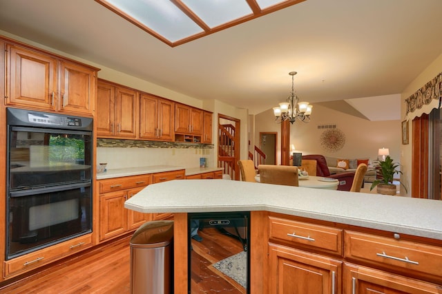 kitchen with an inviting chandelier, black double oven, light wood-type flooring, tasteful backsplash, and beverage cooler