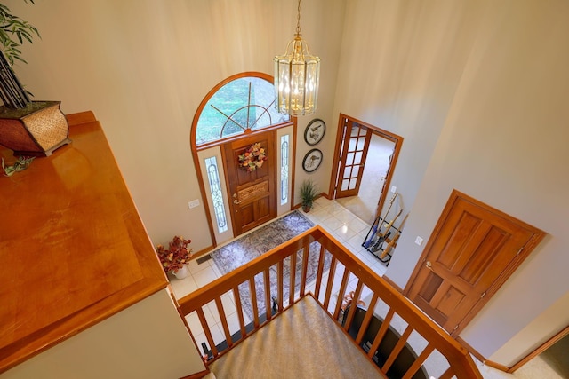 tiled foyer entrance with a chandelier and a towering ceiling