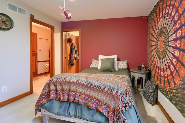 bedroom with connected bathroom, light colored carpet, and a spacious closet