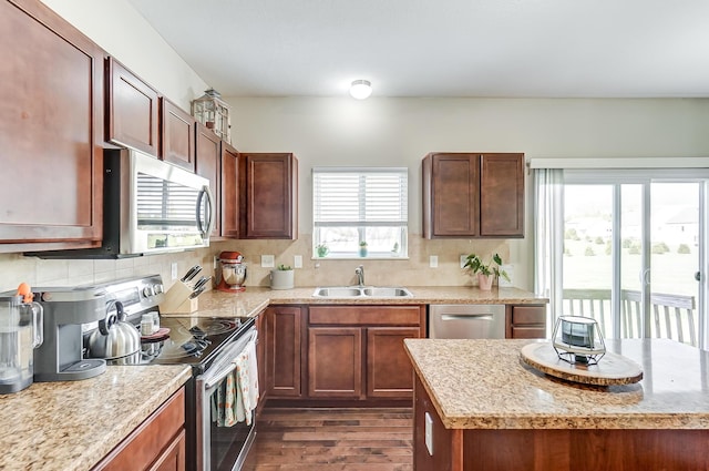 kitchen with light stone countertops, sink, dark wood-type flooring, stainless steel appliances, and decorative backsplash