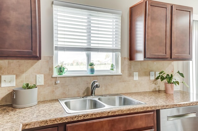 kitchen featuring stainless steel dishwasher, a healthy amount of sunlight, sink, and tasteful backsplash