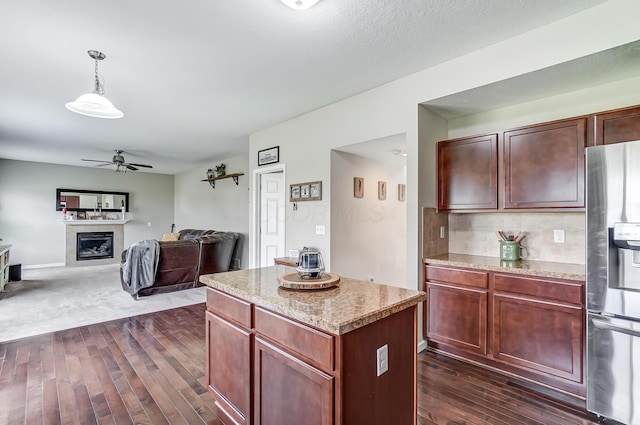 kitchen with a center island, hanging light fixtures, dark hardwood / wood-style floors, ceiling fan, and stainless steel fridge with ice dispenser