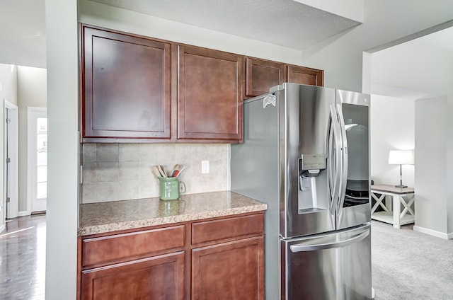 kitchen featuring decorative backsplash, light carpet, and stainless steel refrigerator with ice dispenser