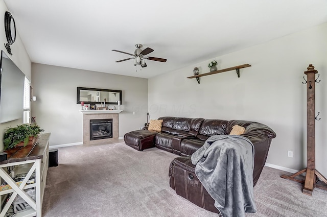 carpeted living room with ceiling fan and a tiled fireplace