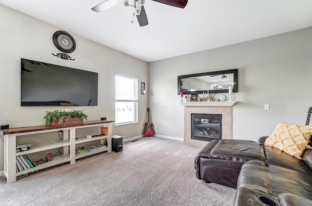 living room with ceiling fan, light colored carpet, and a tiled fireplace