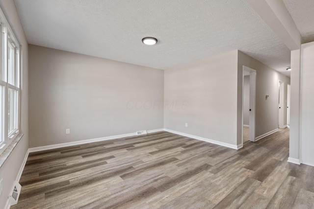 unfurnished room featuring plenty of natural light, wood-type flooring, and a textured ceiling