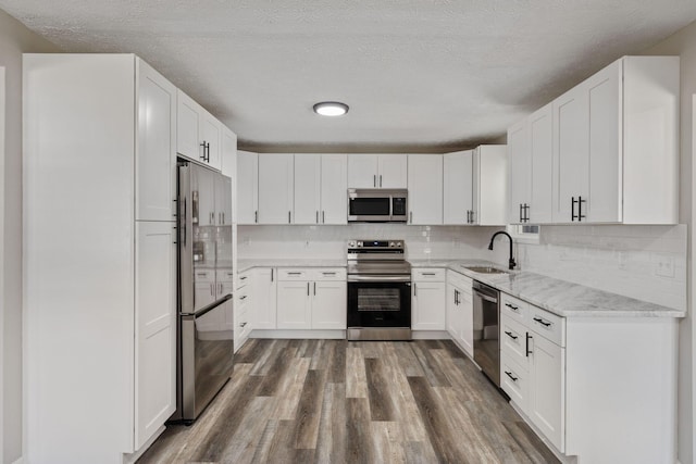 kitchen with sink, dark wood-type flooring, a textured ceiling, white cabinets, and appliances with stainless steel finishes