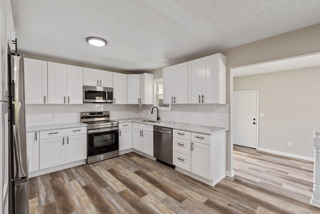 kitchen featuring white cabinets, light hardwood / wood-style floors, a textured ceiling, and appliances with stainless steel finishes