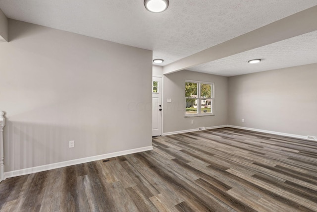 spare room with a textured ceiling and dark hardwood / wood-style flooring