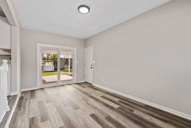 spare room featuring a textured ceiling and light hardwood / wood-style flooring