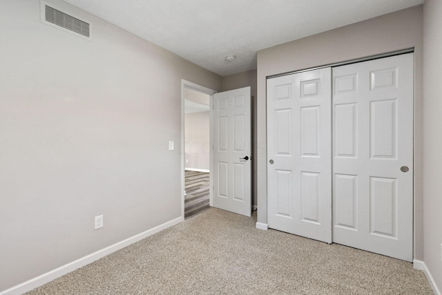 unfurnished bedroom featuring light carpet and a closet