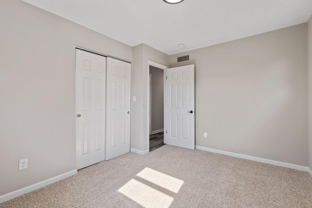 unfurnished bedroom with a closet and light colored carpet