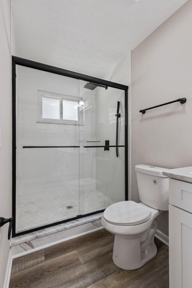 bathroom featuring hardwood / wood-style floors, vanity, a shower with door, toilet, and a textured ceiling