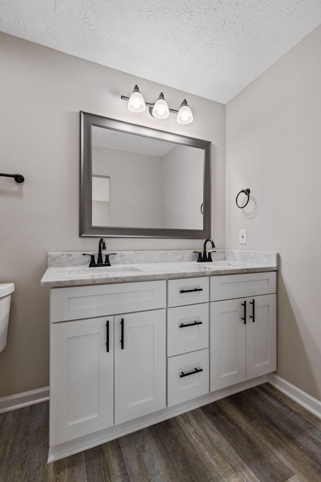 bathroom featuring vanity, wood-type flooring, and a textured ceiling