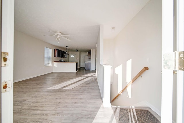 interior space with ceiling fan, light hardwood / wood-style floors, and a textured ceiling