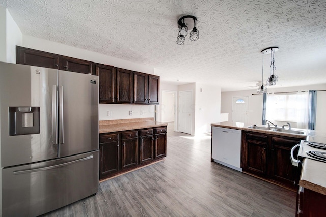 kitchen with wood-type flooring, white appliances, a textured ceiling, and dark brown cabinetry