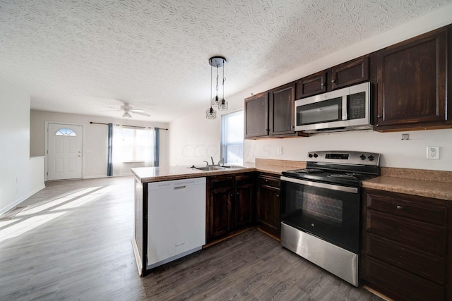 kitchen featuring sink, stainless steel appliances, dark hardwood / wood-style floors, kitchen peninsula, and pendant lighting