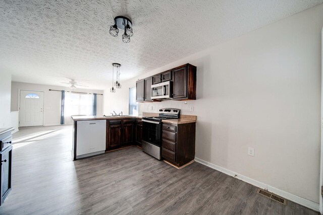 1109 Fairwood Ave, Columbus, OH 43206 - kitchen featuring stainless steel appliances, a peninsula, dark brown cabinetry, wood finished floors, and light countertops