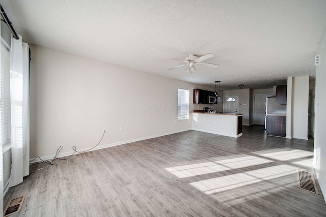 unfurnished living room featuring a textured ceiling, ceiling fan, and dark wood-type flooring