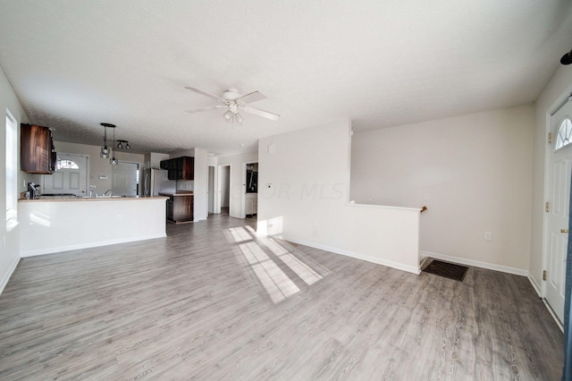 unfurnished living room featuring ceiling fan, hardwood / wood-style floors, and a textured ceiling