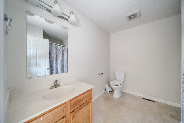 bathroom with vanity, toilet, and a textured ceiling