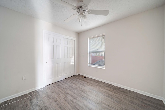 unfurnished bedroom featuring ceiling fan, wood-type flooring, a textured ceiling, and a closet