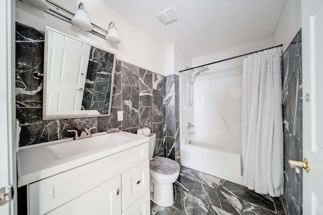 full bathroom featuring shower / bath combo, vanity, toilet, a textured ceiling, and tile walls