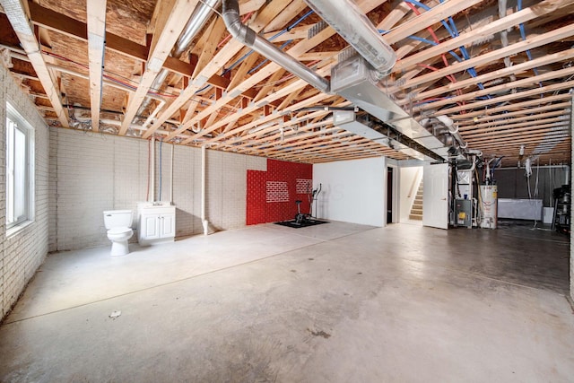 basement featuring heating unit, water heater, and brick wall