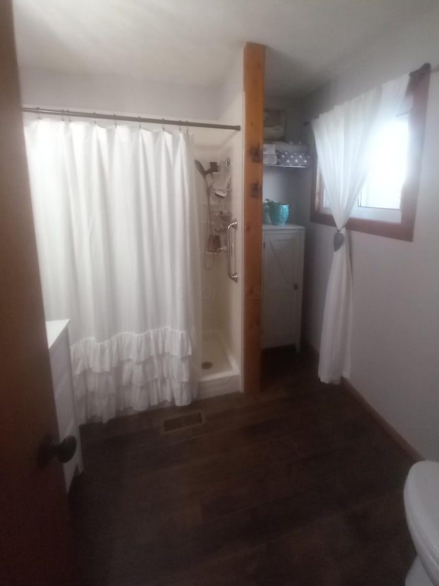 bathroom featuring hardwood / wood-style floors, a shower with curtain, and toilet