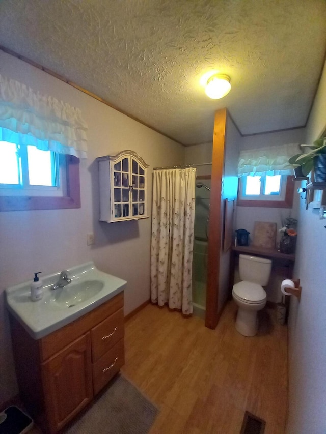 bathroom featuring curtained shower, wood-type flooring, a textured ceiling, and a wealth of natural light