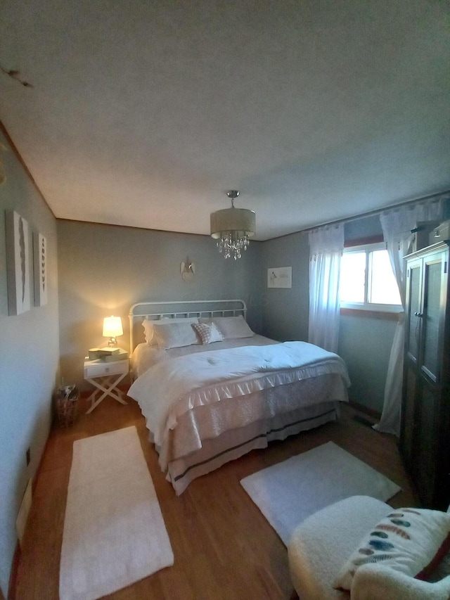 bedroom featuring a notable chandelier and hardwood / wood-style flooring