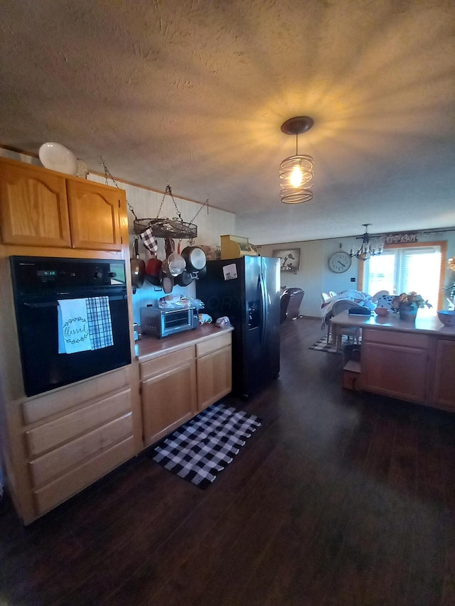 kitchen with hanging light fixtures, black appliances, dark hardwood / wood-style floors, and an inviting chandelier