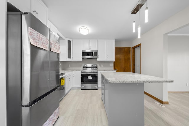5608 Cardinal Dr, Orient, OH 43146 - kitchen featuring appliances with stainless steel finishes, white cabinets, a center island, light stone counters, and light wood finished floors