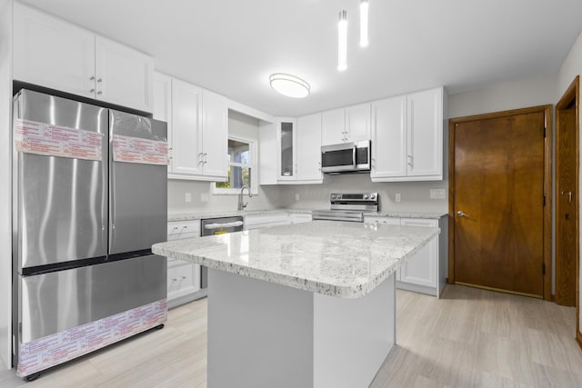 5608 Cardinal Dr, Orient, OH 43146 - kitchen with stainless steel appliances, white cabinetry, a center island, light stone counters, and glass insert cabinets