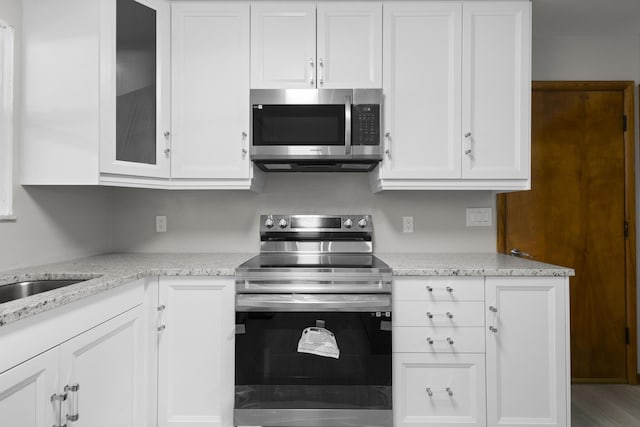 5608 Cardinal Dr, Orient, OH 43146 - kitchen featuring stainless steel appliances, white cabinetry, light stone countertops, and glass insert cabinets