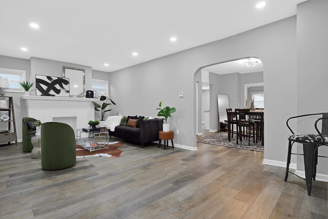 living room featuring light wood-type flooring, a brick fireplace, and a wealth of natural light