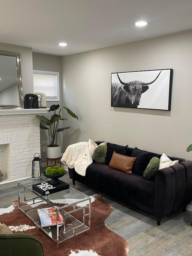 living room with hardwood / wood-style floors and a brick fireplace