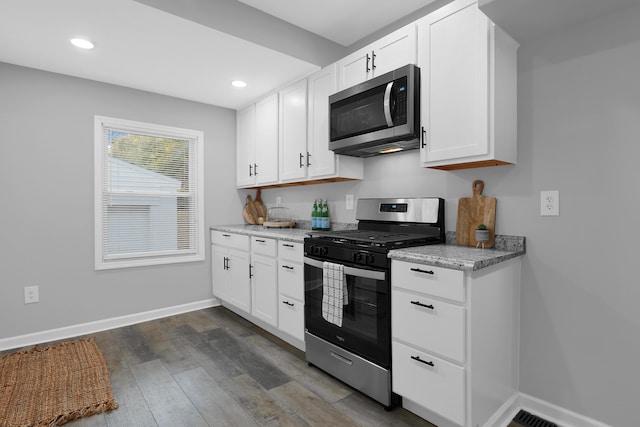 kitchen featuring light stone countertops, dark hardwood / wood-style flooring, white cabinets, and appliances with stainless steel finishes