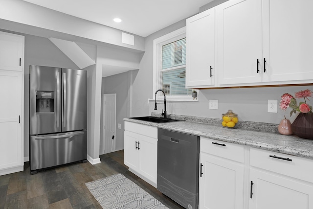 kitchen with appliances with stainless steel finishes, light stone counters, dark wood-type flooring, sink, and white cabinets