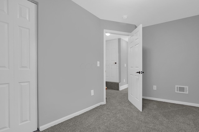 unfurnished bedroom featuring dark carpet and a closet