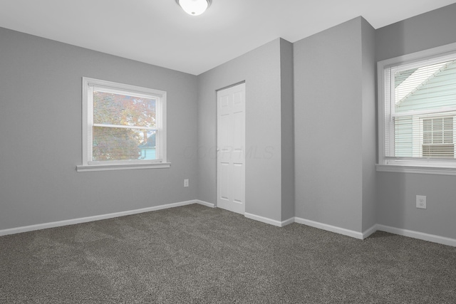 unfurnished bedroom featuring dark colored carpet and a closet