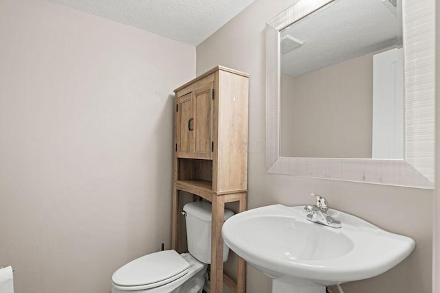 bathroom featuring toilet, sink, and a textured ceiling