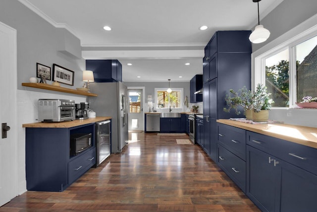 kitchen with appliances with stainless steel finishes, ornamental molding, blue cabinets, wine cooler, and hanging light fixtures